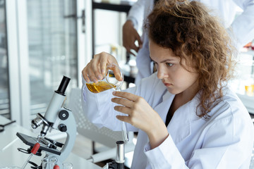 Young scientist researcher examining chemical liquid in test tube in modern laboratory. Science and medicine concept