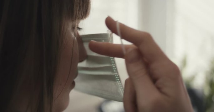 Woman put on face mask protection virus coronavirus at home quarantine close up unrecognizable