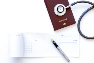 Cheque book, passport and medical stethoscope isolated on white background. Top view.