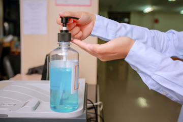 Female office cleaning hand  using alcohol gel sanitizer  for anti becteria and protect from Coronavirus Disease 2019 on office desk, Stack of business paper.