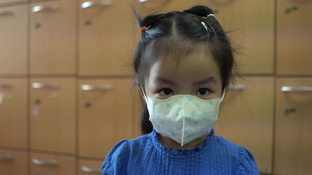 A little girl wearing a face prevent the spread of the Covid-19 beside the locker in building., Covic 19 virus protection concept in Thailand.