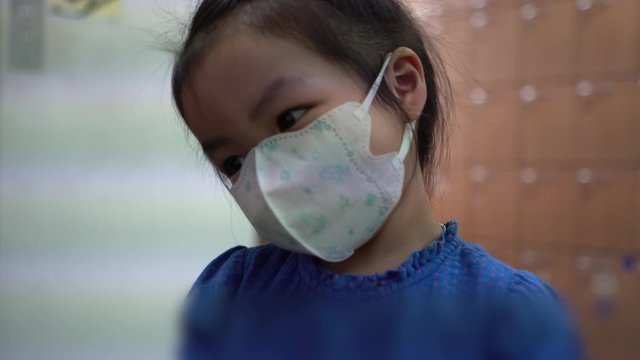  A little girl wearing a face prevent the spread of the Covid-19 beside the locker in building., Covic 19 virus protection concept in Thailand.