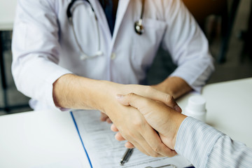 Doctor shaking hands with older patient in the clinic room.