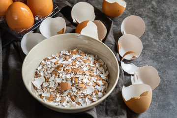selective focus of cracked eggshells and grinded eggshells on dark stone table