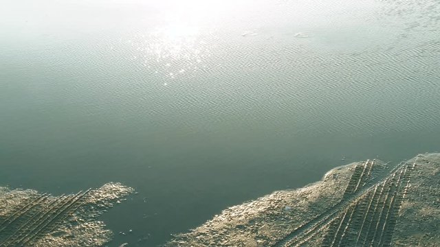 Back crawl of flowing water leading into wet tire tracks