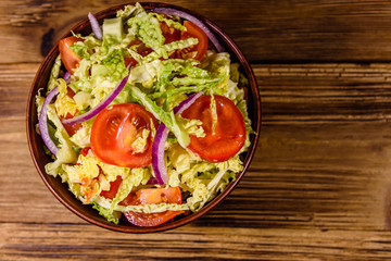 Vegan salad with savoy cabbage, tomatoes and onion in a ceramic bowl. Top view