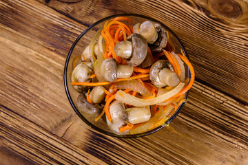 Canned mushrooms with carrot and onion in a ceramic bowl. Top view