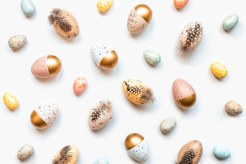 Top view of scattered Easter eggs colored with golden paint in different patterns. White background.