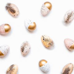 Top view of scattered Easter eggs colored with golden paint in different patterns. White background.