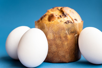 Easter composition from a small Easter cake and three white chicken eggs on a classic blue...