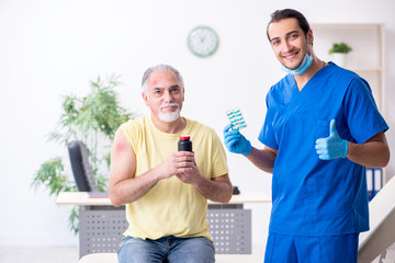 Fototapeta premium Injured old man visiting young male doctor traumatologist