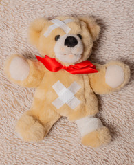 Kranker Teddybär liegt auf eine Felldecke 