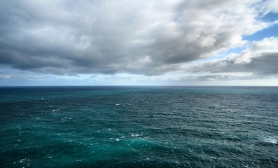 Fototapeta na wymiar Calm deep sea with dramatic clouds and sky.