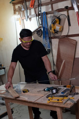 Handsome man wearing protective glasses,doing wood work at factory,Handmade design,The carpenter