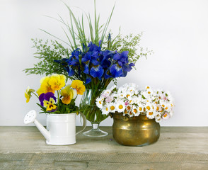 Still life with small bouquets of flowers on wooden table on white background. Cover design