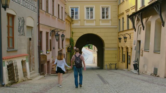 Tourist Couple Holding Hands While Walking On The Street In Lublin, Poland - Perfect for Summer Vacation - Wide Shot