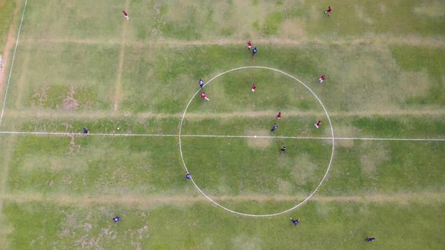Zenital drone footage of a soccer game. Drone gains altitude.