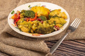 Vegetable salad in a white ceramic bowl and fork on a background of rough homespun fabric. Close up.