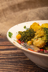 Vegetable salad in a white ceramic bowl on a background of rough homespun fabric. Close up.