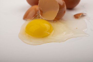 Broken chicken egg and chicken eggs scattered on a white background. Close up.