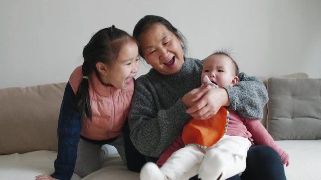 Senior asian woman playing with her two granddaughter at home happy grandmother having fun with two little girl people lifestyles at home