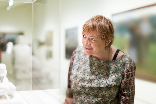 Smiling pensioner woman watching at sculpture