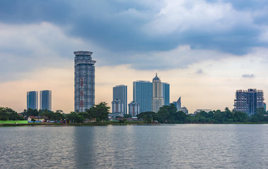 Fototapeta na wymiar Tangerang, Indonesia - 5th January 2018: A view of Kelapa Dua Lake in the foreground and Lippo Karawaci district buildings in the background. Taken in a cloudy afternoon. Property investment.