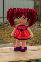Doll Amigurumi girl Stesha, stands outdoors in a swarm dress.