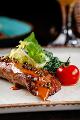 Spanish cuisine. Veal steak with spinach and cream. Red wine is on the table. girl holding in hands a knife and a fork in a restaurant. background image, copy space text