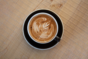  A flat lay black cup of coffee placed on a wooden table by the window in shop,  Concept: Delicious breakfast drinks fragrant suitable for lifestyle, closeup cup of coffee over the top with space 