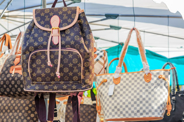 Fake high-end famous designer purses and backpacks for sale at a local outdoor flea market in...