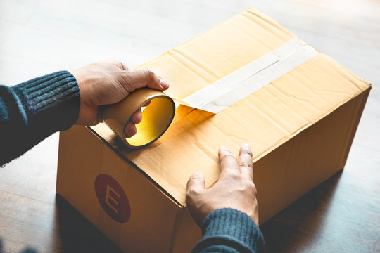 Close up male hand wrapping packaging box by tape.Business online shopping.logistic transportation service
