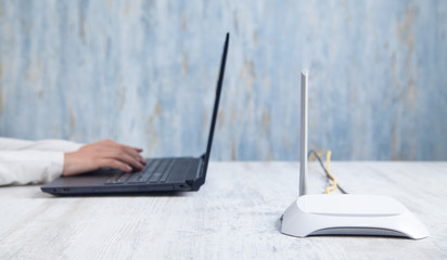 Internet router in the desk. Girl using laptop
