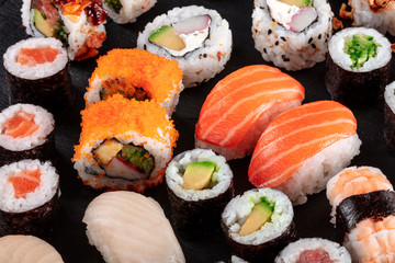 Large sushi set on black. An assortment of various maki, nigiri and rolls