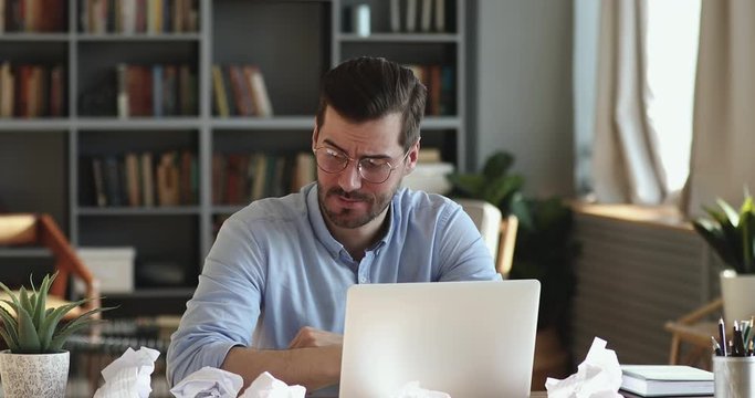 Overworked businessman checking time falling asleep at work desk. Tired male worker yawning taking nap at messy table with crumpled papers. Exhausted employee workaholic sleeping in office concept