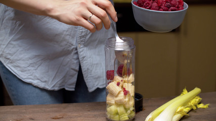 Woman pouring raspberries in blender glass