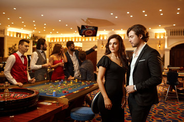 Beautiful glamour couple against the background of casino poker roulette.