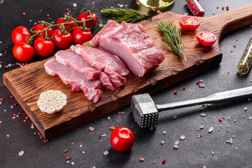 Fresh pieces pork ready to cook on a dark background in the kitchen