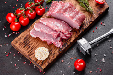 Fresh pieces pork ready to cook on a dark background in the kitchen