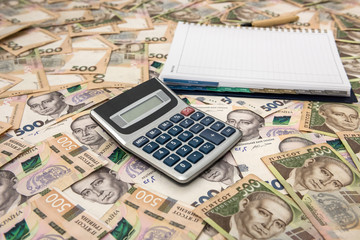 Empty notepad with calculator on Ukrainian Money backgrounds. 500 banknotes. Hryvnia (UAH). Top view