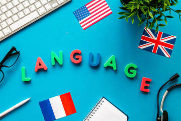Learn foreign language online. Concept with text, headset and keyboard on blue background top-down