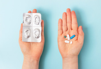 Female hands hold a blister and pills on blue background top view.