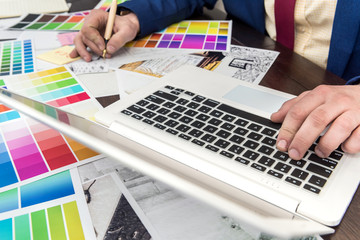 Architect choosing colors for building decoration of room interior with laptop and color sample.