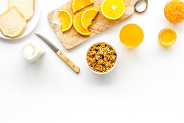 Morning granola near toast and oranges on white background top-down frame copy space