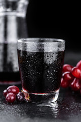 Fresh made Red Grape Juice on a slate slab (close-up shot; selective focus)