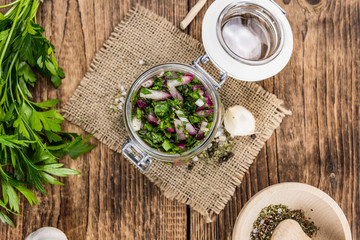 Wooden table with Chimichurri (detailed close-up shot; selective focus)