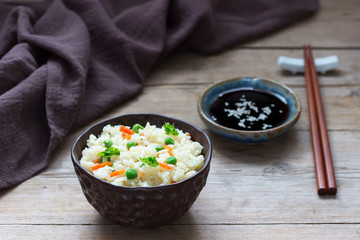 Vegetarian rice dish with vegetables and green peas on a wooden background.