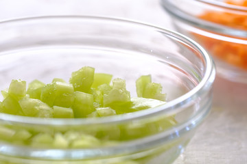 finely chopped green bell peppers and carrots in a glass cup on a gray background