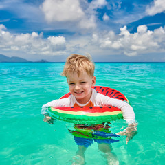 Toddler boy on beach swimming with inflatable ring