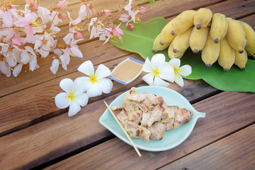 Banana grill with Simmer coconut sugar and fresh banana on top the banana leaf on the wooden table.vintage filter and selective focus.